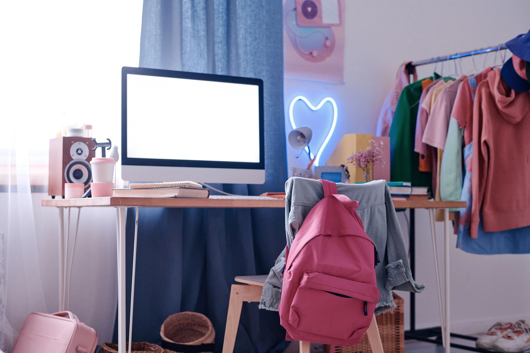 Workspace with computer and clothing rack, representing a modern tailoring studio