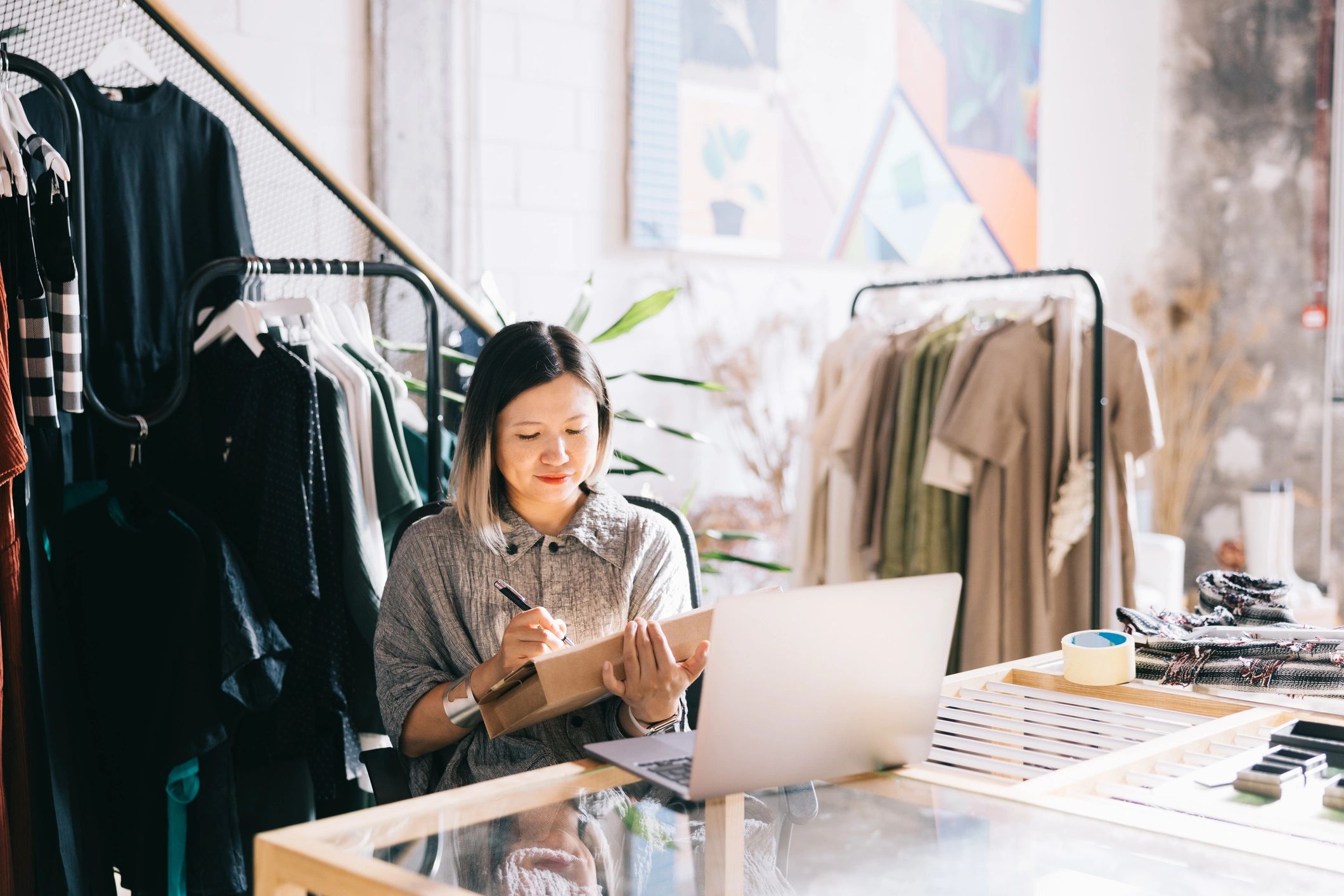 Fashion business owner working at a counter with a laptop open